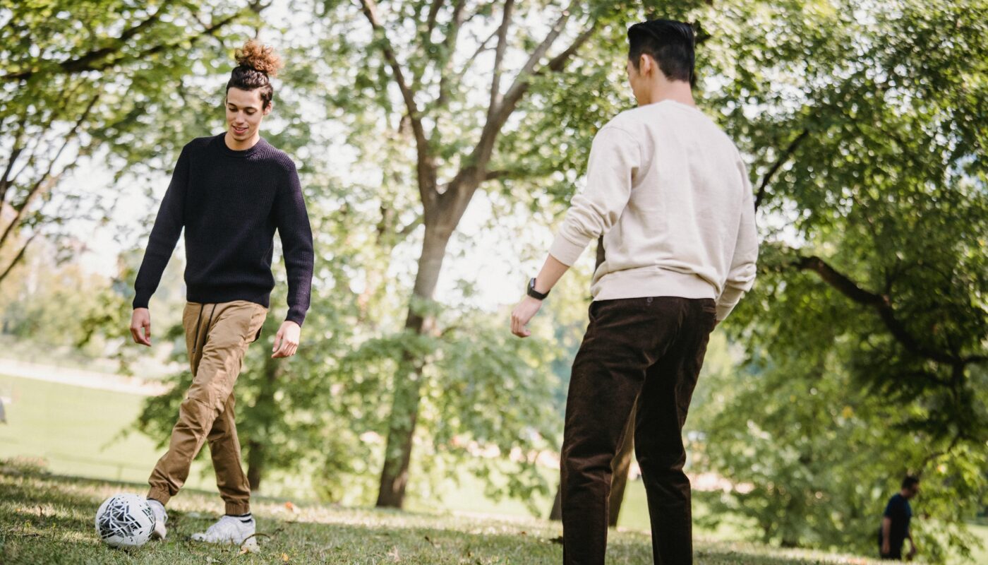 https://www.pexels.com/photo/positive-ethnic-male-friends-playing-football-in-park-5553089/