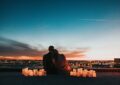 couple sitting on the field facing the city