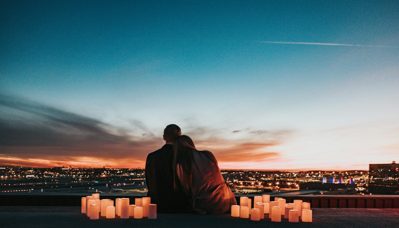 couple sitting on the field facing the city